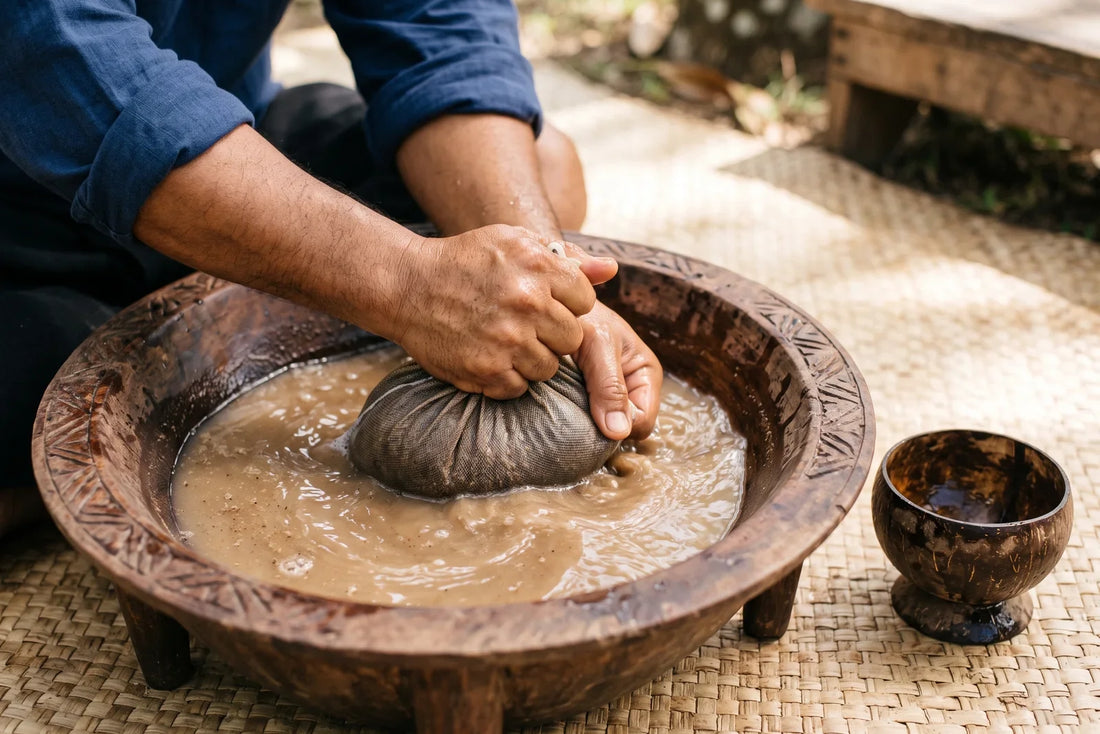 Hands straining kava through a mesh bag in a carved wooden bowl