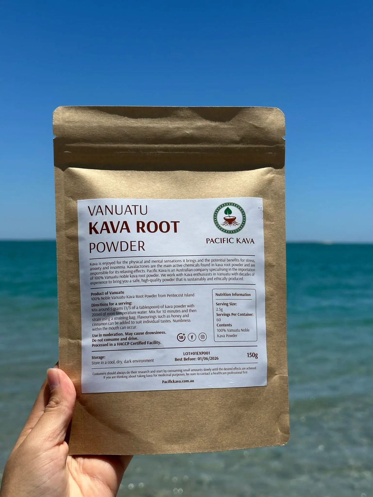 Hand holding a Borogoru kava powder pouch against the sea